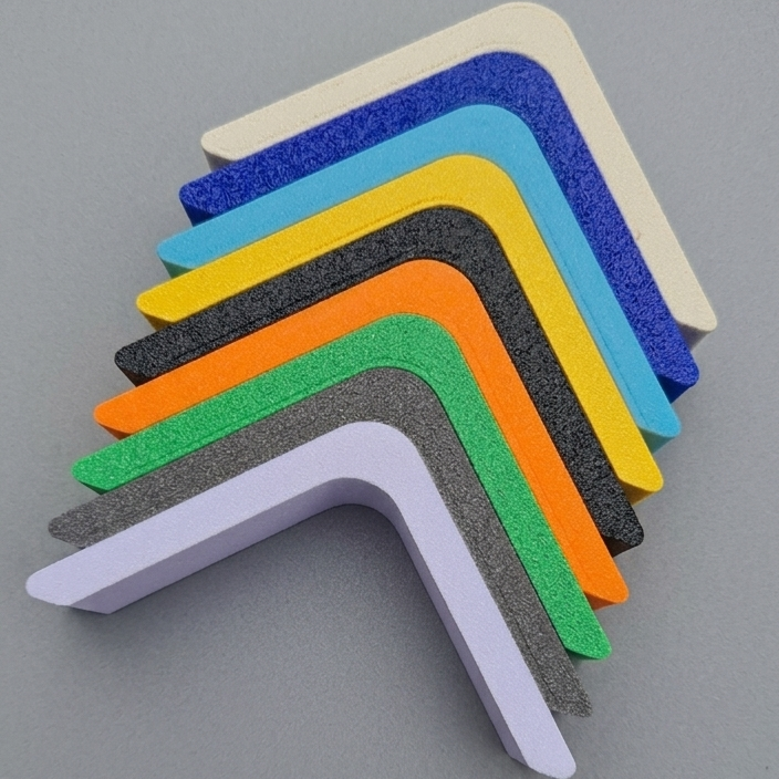 Stack of 3D printed L-shaped profile corner samples showcasing multiple color options on a smooth grey surface